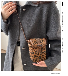 Detail of leopard print shoulder bag with horn buckle and leather strap on a model