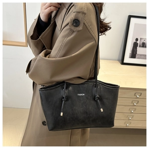 Detail view of black vintage tote bag with fashion text and knot handle on a model