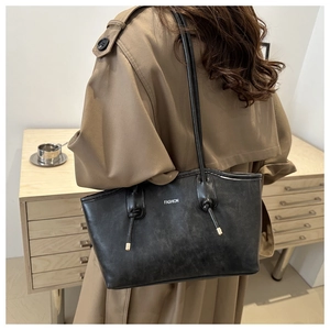Detail of vintage black leather tote bag with FASHION logo and knotted shoulder strap