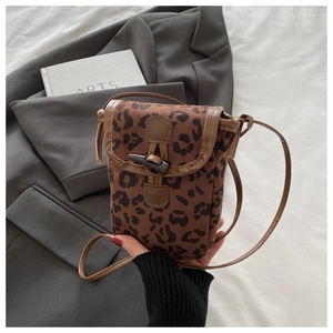 Close-up of leopard print crossbody phone bag with faux suede texture and horn button detail