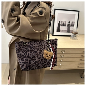 Dettaglio della borsa tote leopardata con tracolla a catena e ciondolo a orsetto