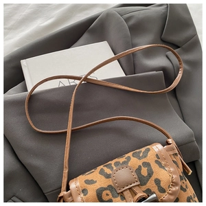 Close-up of leopard print crossbody bag with horn buckle on a stylish blazer