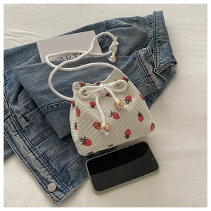 Detail of off-white corduroy bucket bag with strawberry print on denim jacket background