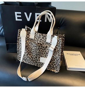 Detail of leopard print tote bag with adjustable wide strap on a premium leather sofa