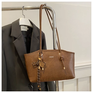 Close-up of brown vintage tote bag with fashion lettering and tennis racket pendant details