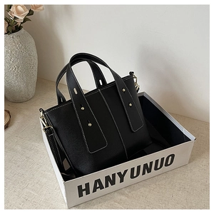 Detailed shot of a black pebble leather tote bag with white stitching in a gift box