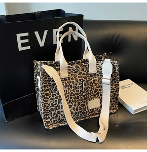 Detail of leopard print tote bag with white webbing straps and external pockets