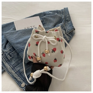 Detail view of strawberry print bucket bag with white drawstring and gold bead accents