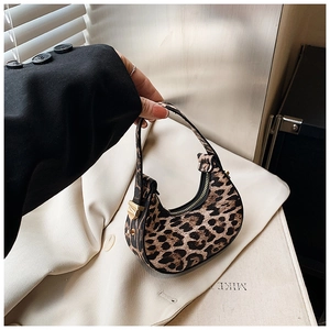 Macro detail of leopard print crescent bag featuring gold metal hardware and black zipper