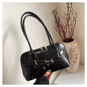 Detailed macro view of black patent leather shell bag with golden metal hardware and zipper