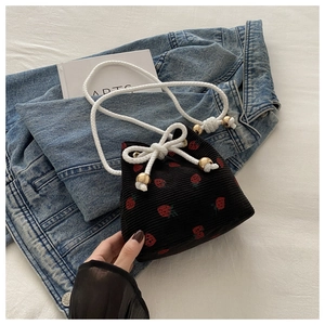 Detail of black corduroy bucket bag with strawberry embroidery and drawstring