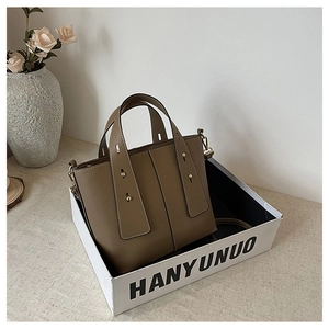Detailed close-up of brown pebbled leather tote bag with vertical stitching and gold rivets