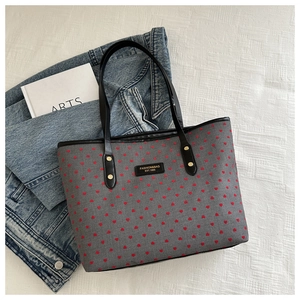 Close-up of gray canvas tote bag featuring red heart embroidery and black shoulder strap