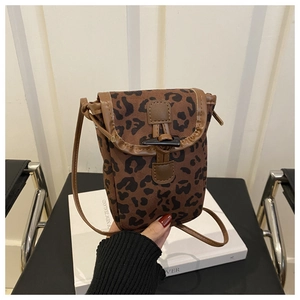 Detail of leopard print crossbody phone bag featuring a vintage horn button and leather trim