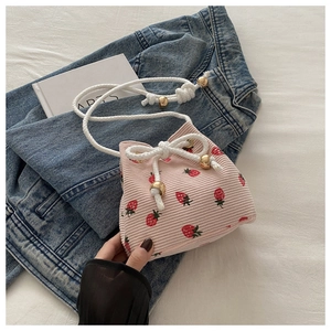Detail of pink corduroy strawberry bucket bag with white rope straps and golden beads
