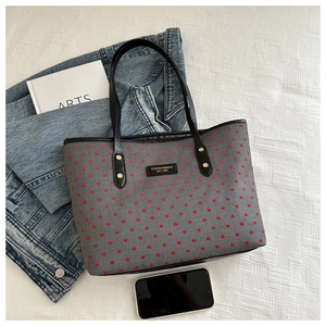 Flat lay of gray tote bag with red hearts alongside denim jacket and phone