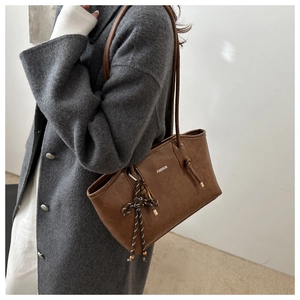 Detail of vintage brown tote bag with white FASHION print and woven knotted charm