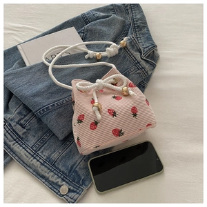 Detail of pink corduroy strawberry bucket bag with drawstring and gold metal accents
