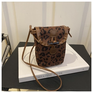 Detailed close-up of leopard print phone bag with horn buckle on white book