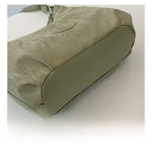 Close-up of sage green shoulder bag showing soft pleated texture and smooth base detail