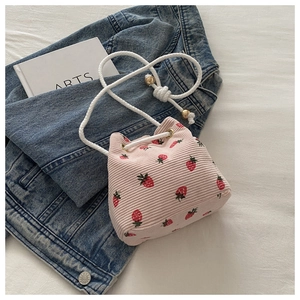 Close-up of pink corduroy strawberry bucket bag with white rope strap and gold beads
