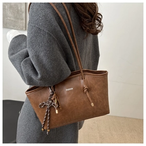 Detail of brown PU leather tote bag with FASHION print and woven rope charm pendant