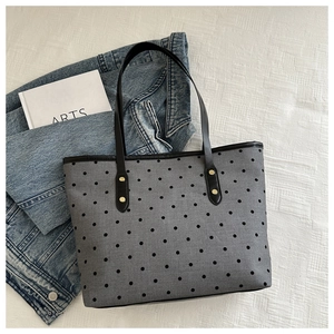 Detail of grey fabric tote bag with black polka dots and gold rivet strap accents