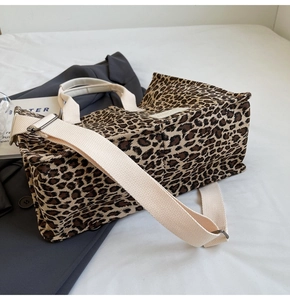 Detail view of canvas leopard print tote bag with adjustable strap and top handles