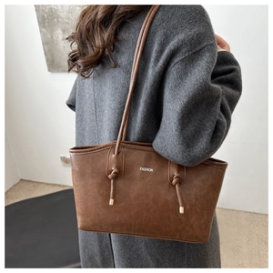 Detail view of a vintage dark brown leather tote bag with knotted straps and gold tips