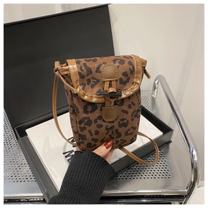 Detail of leopard print crossbody phone bag with brown leather trim and toggle closure