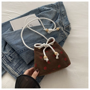 Detail of corduroy drawstring bucket bag with cute strawberry print on denim background