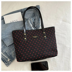 Detail of black tote bag with red hearts and fashion leather patch on textured fabric