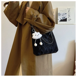Detail of black glossy shoulder bag with silver chain and cute white cloud pendant