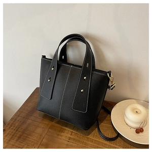 Detail of black pebbled leather tote with white contrast stitching and gold studs