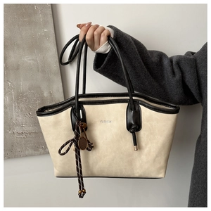Detail of a beige PU leather tote bag with FASHION lettering and tennis racket charm
