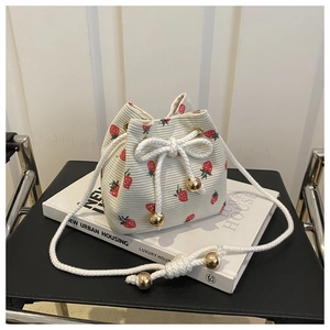 Detail of strawberry print corduroy bucket bag with drawstring and gold metal charm