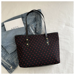 Detail view of heart print tote bag with reinforced leather handles and metal rivets