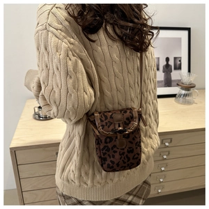 Detailed view of leopard print crossbody phone bag with brown leather trim and horn buckle