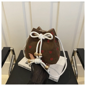 Detailed close-up of brown corduroy bucket bag with strawberry print and rope drawstring