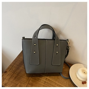 Detail of grey lychee leather tote with white contrast stitching and gold rivets