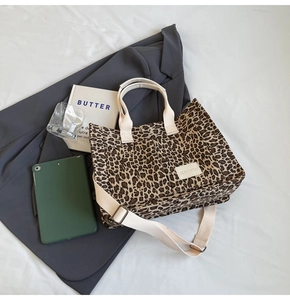 Detail showing leopard print canvas tote bag texture with adjustable cream strap