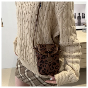 Detail showing leopard print phone bag with brown leather trim and drawstring closure