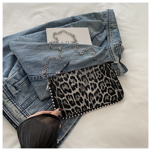 Detailed close-up of leopard print shoulder bag with silver studs and metal chain