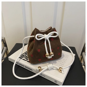 Close-up of brown corduroy bucket bag featuring red strawberry prints and drawstring detail