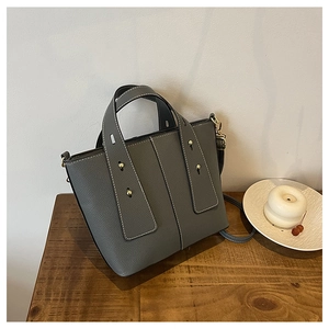 Detailed view of dark grey pebble leather tote with white stitching and gold studs