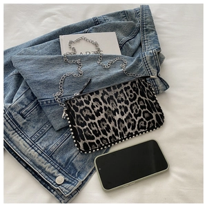 Detailed view of leopard print crossbody bag with silver stud trim and chain strap