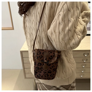 Close-up of leopard print crossbody phone bag with vintage buckle and slim strap