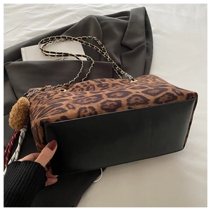 Dettaglio della borsa tote leopardata con catena dorata e ciondolo a pompon morbido