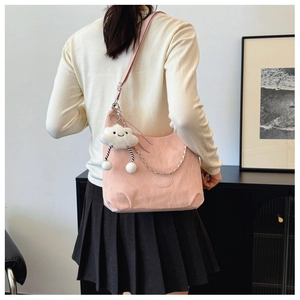 Detailed close-up of pink nylon shoulder bag with white plush cloud charm and metal chain strap