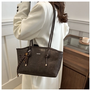 Detail of dark brown matte leather tote bag featuring fashion print and key charm